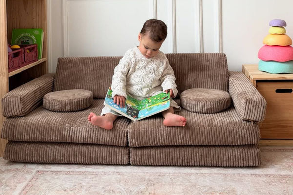 Lapsi lukemassa suklaanruskealla Shappy Mini Pure Corduroy -leikkisohvalla